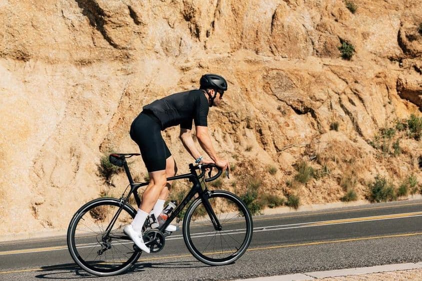 Ciclista con ropa deportiva negra en intenso entrenamiento al aire libre.