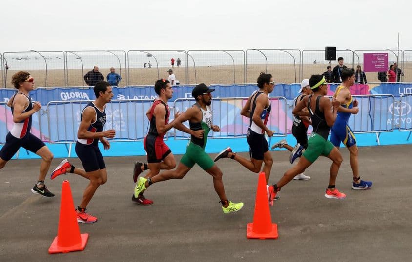 Participantes de triatlón corriendo en la playa.