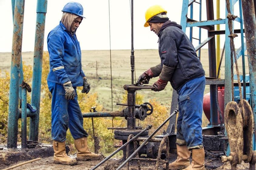Trabajadores petroleros inspeccionando una bomba de petróleo.