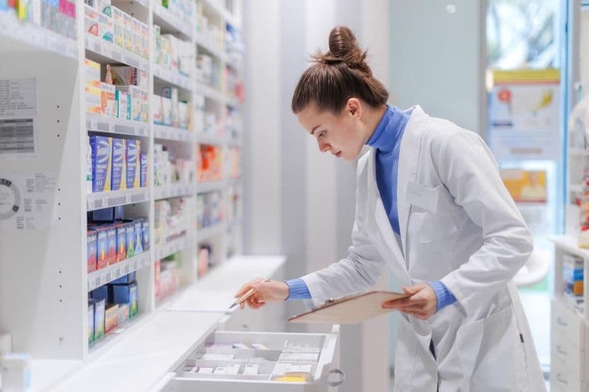 Farmacéutico joven revisando el stock de medicinas en una farmacia.