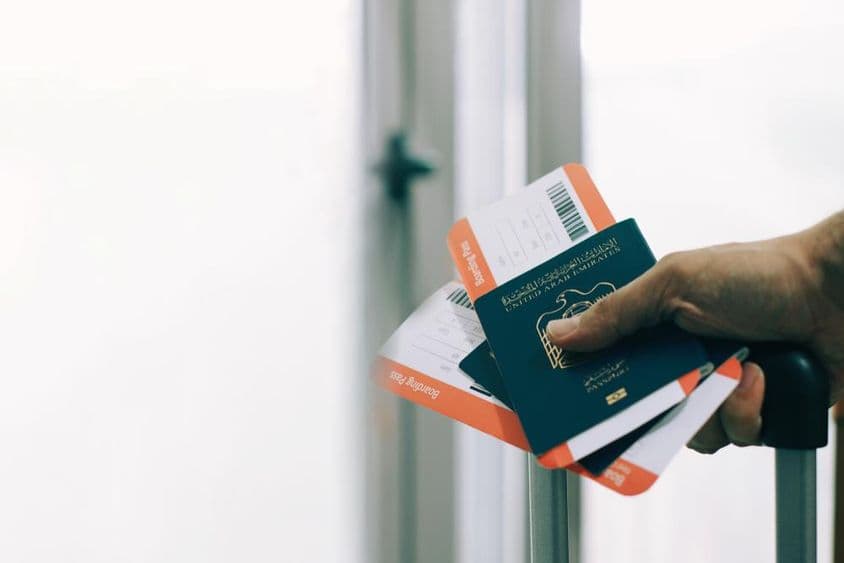 Un pasajero en el aeropuerto con un pasaporte de los Emiratos Árabes Unidos y un boleto de vuelo.