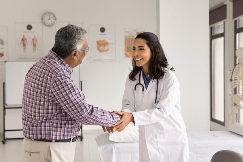 Joven doctora sonriente examinando a un paciente.