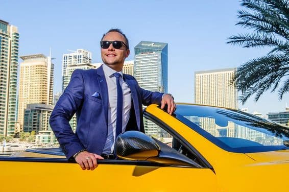 Un empresario exitoso en un coche convertible amarillo.
