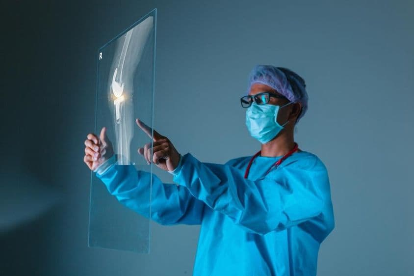 Doctor sosteniendo imagen de Rayos X de hueso del paciente antes de cirugía.