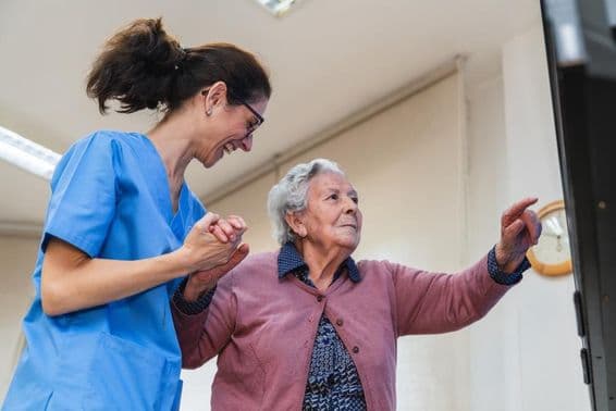 Mujer anciana recibiendo ayuda de una enfermera en un hogar de cuidado.