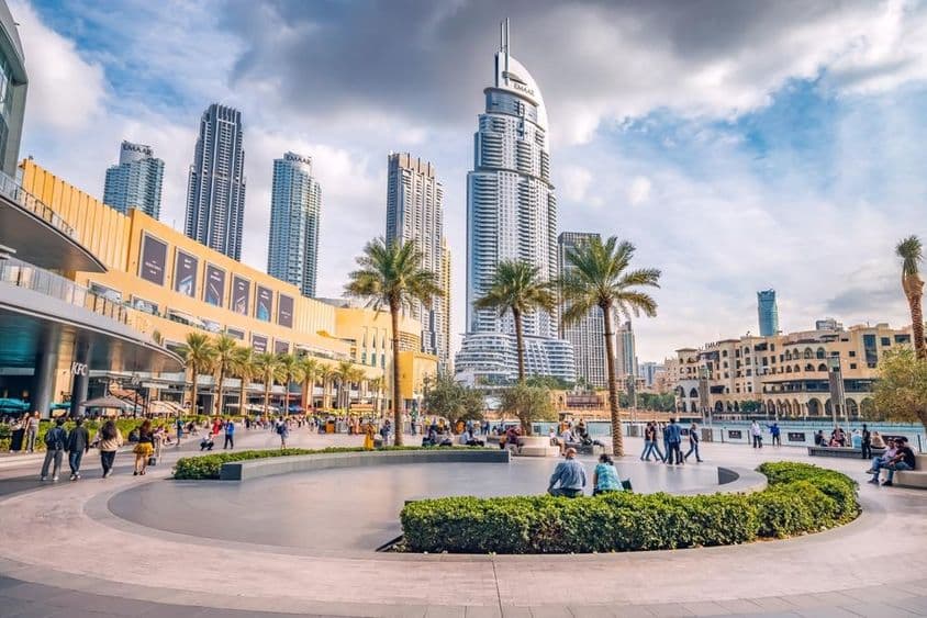 Multitudes de turistas caminando por la plaza y el paseo cerca de la entrada del Dubai Mall.