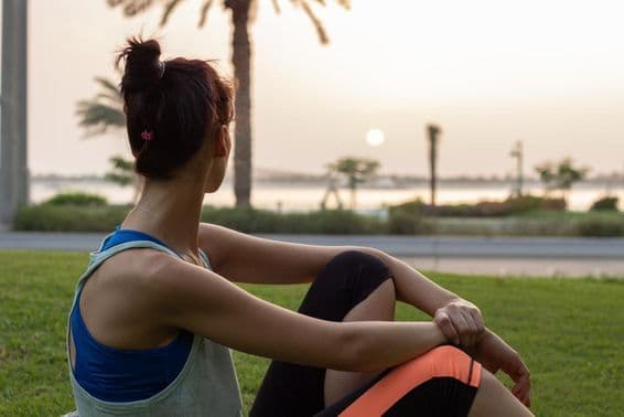 Niña joven descansando después de yoga en un parque en la Corniche de Abu Dhabi.