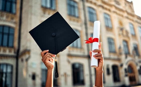 Birrete de graduación y diploma con cinta roja.
