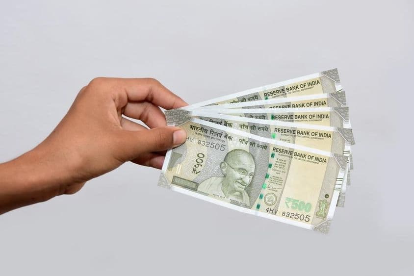 Un hombre sosteniendo un nuevo billete de 500 rupias indias.