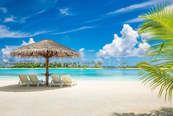 Playa de arena en Maldivas con sombrilla y silla de playa.