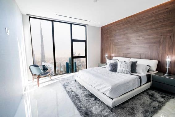 Dormitorio de lujo con techo blanco y moldura de madera, con vista al centro de Dubái.
