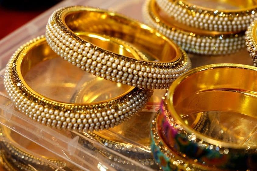 Brazaletes de oro ornamentados apilados juntos.