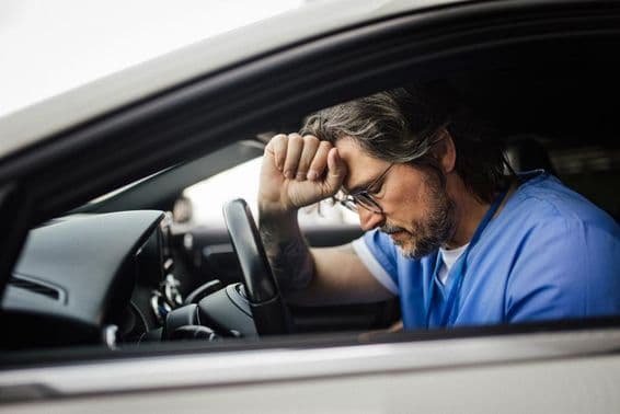 Médico en coche, exhausto.