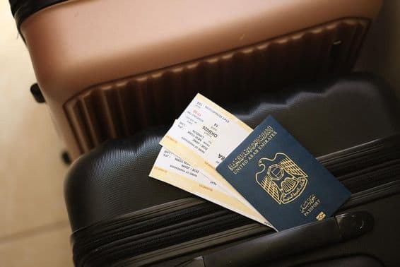 Emiratos Árabes Unidos, un pasaporte con boletos sobre una maleta.