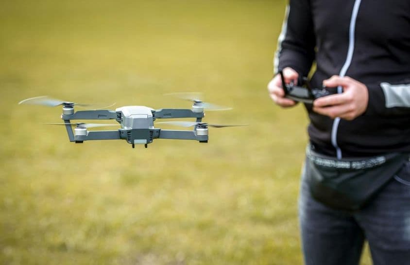 Un hombre controlando un dron con un control remoto.