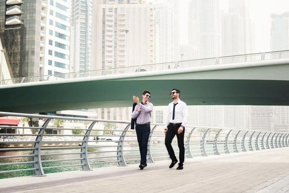 Dos empresarios conversando mientras caminan en Dubai Marina.