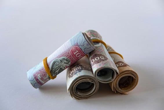 Una colección de monedas y billetes de dirham de EAU enrollados y apilados.