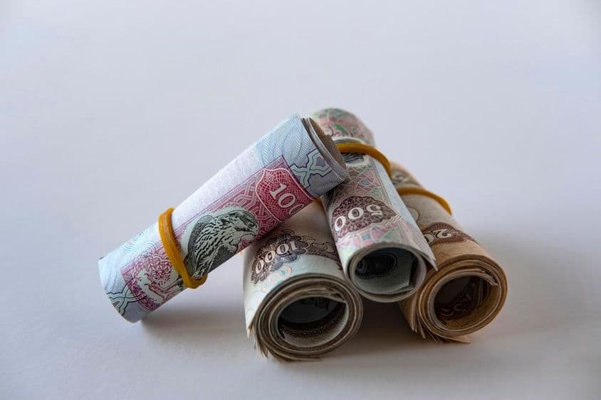 Una colección de monedas y billetes de dirham de EAU enrollados y apilados.