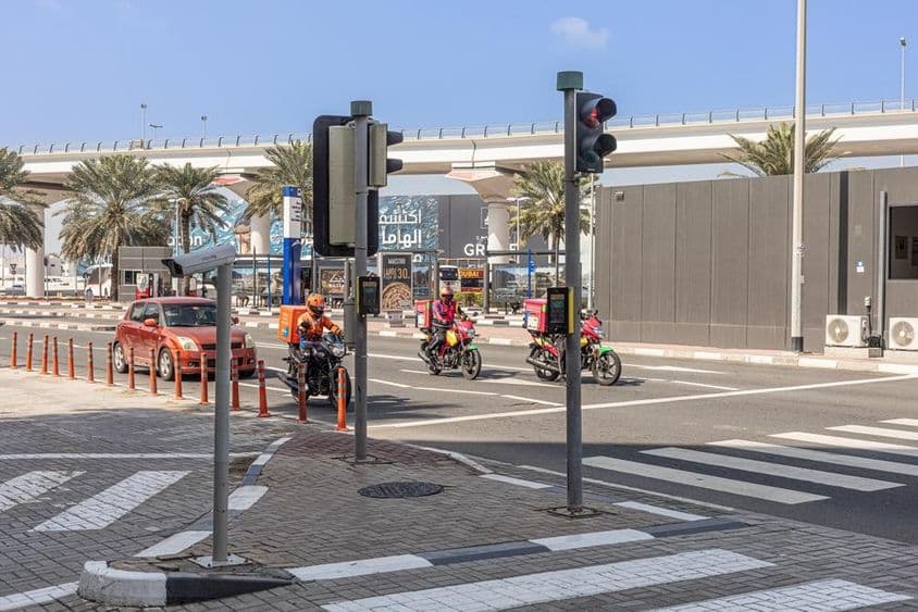 Tres motocicletas y un coche parados en un paso de peatones en Sheikh Zayed Road.