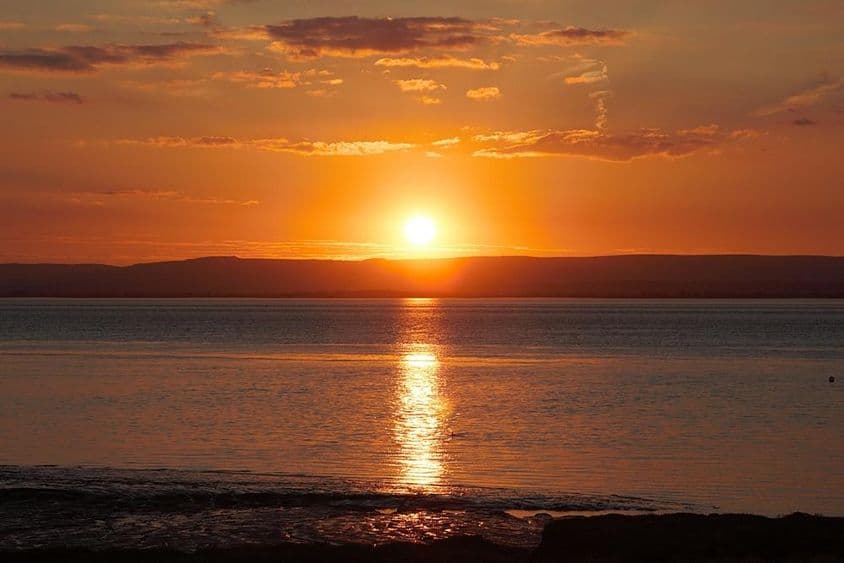 Atardecer reflejándose en el agua y las nubes durante el solsticio de verano.