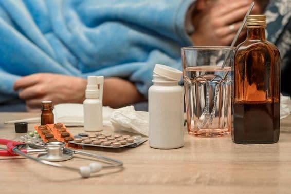 Un hombre con resfriado y fiebre acostado en la cama.