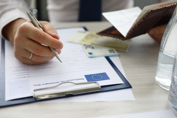 Un hombre sosteniendo un pasaporte e ingresando información personal en una aplicación de visa Schengen.