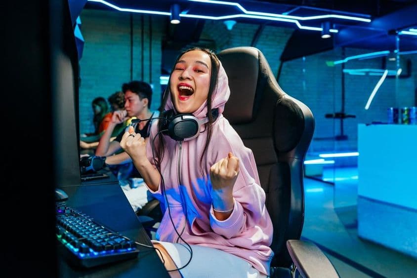 Hermosa joven asiática jugando videojuegos en un cibercafé.