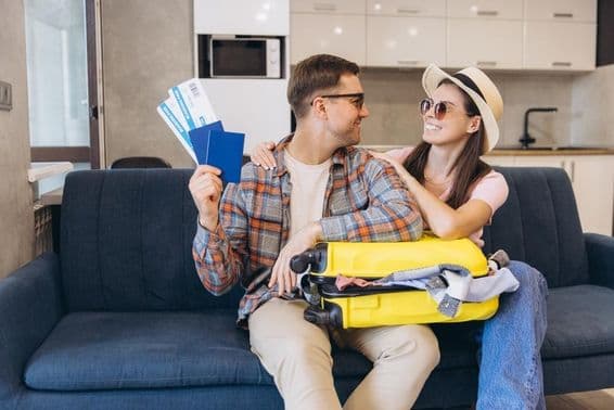 Pareja sonriente con pasaportes y tarjetas de embarque en mano, con una maleta.