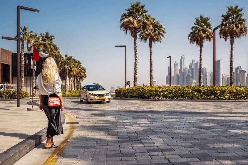 Una mujer en Dubái esperando un taxi en la calle.