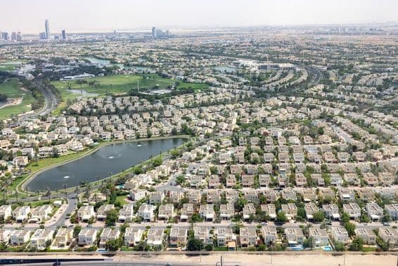 Colinas de los Emiratos en Dubái con casas comunitarias, lago y vegetación.