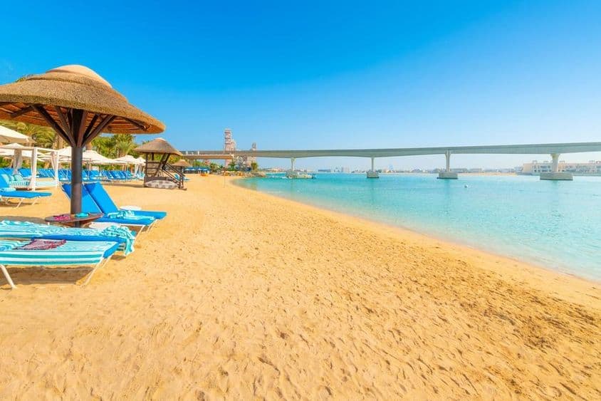 En una playa arenosa del Golfo Arábigo, el monorraíl de la Isla Palm Jumeirah cruza el mar en Dubái.
