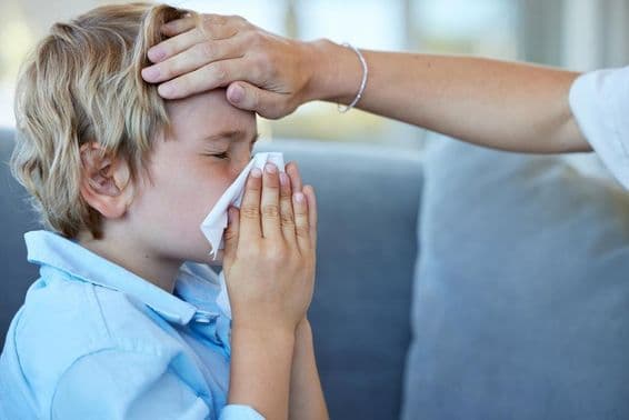Niño enfermo con fiebre en casa en el sofá.
