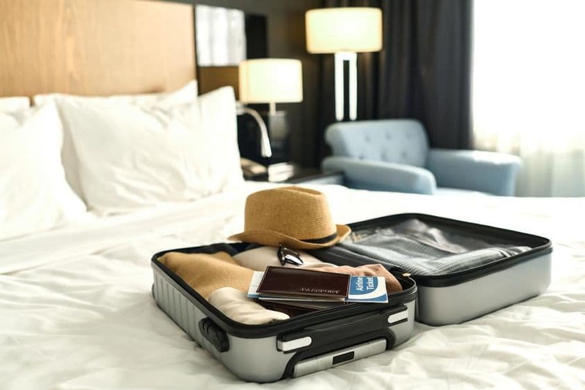 Maleta llena, con pasaporte y boletos sobre una cama.