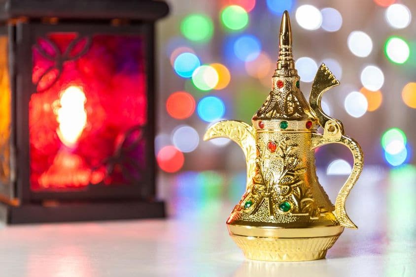 Cafetera árabe y lámpara con luces coloridas y desenfocadas de fondo.