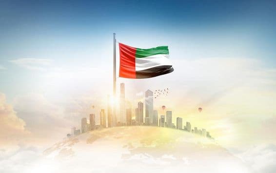 Bandera de Emiratos Árabes Unidos ondeando frente a rascacielos.