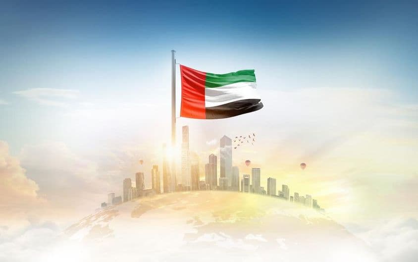 Bandera de Emiratos Árabes Unidos ondeando frente a rascacielos.