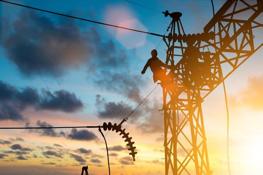 Técnico electricista trabajando en línea de alta tensión.
