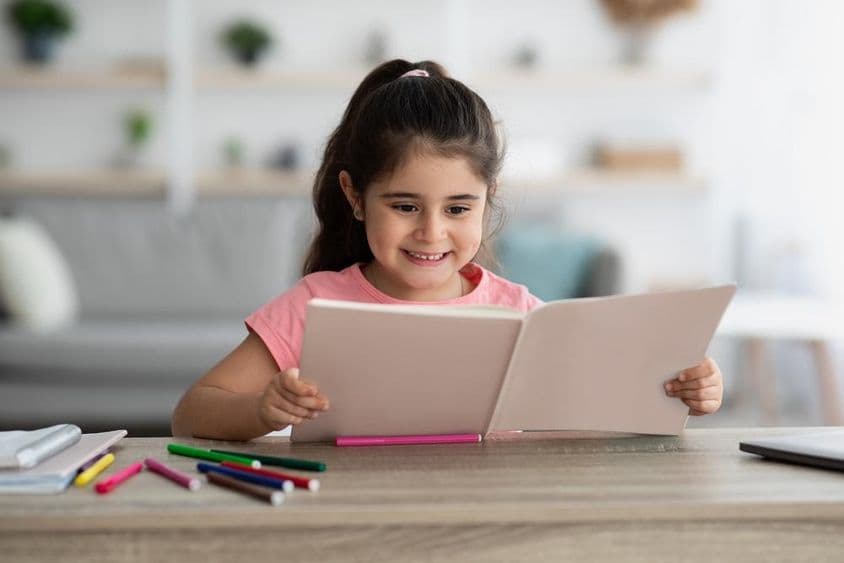 Niño de Medio Oriente estudiando mientras está sentado en un escritorio en casa.