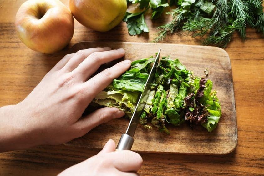 manos femeninas preparando una ensalada para la cena.