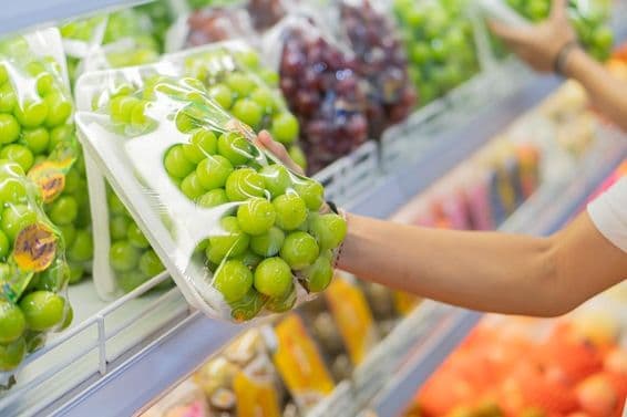 Estantes llenos de varias frutas, incluyendo uvas rojas y otros productos envasados.