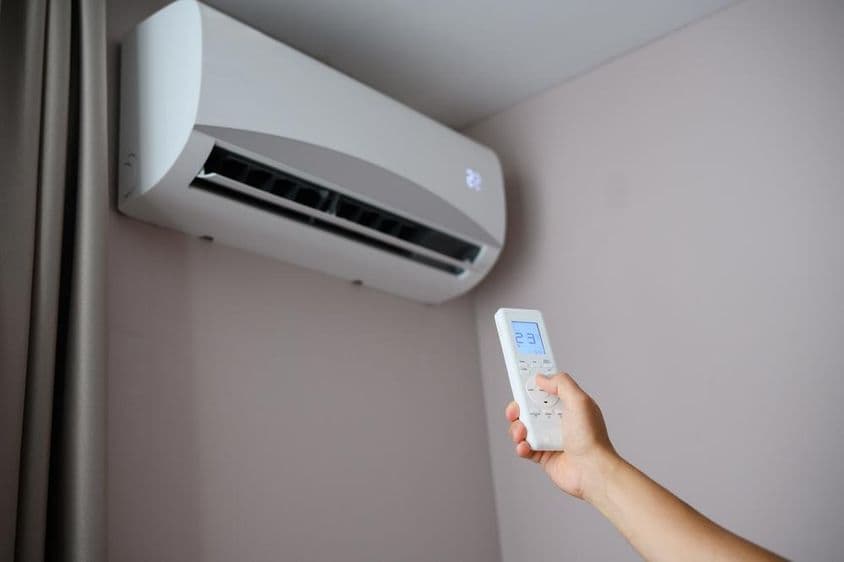 Persona ajusta el aire acondicionado a 22 grados Celsius.
