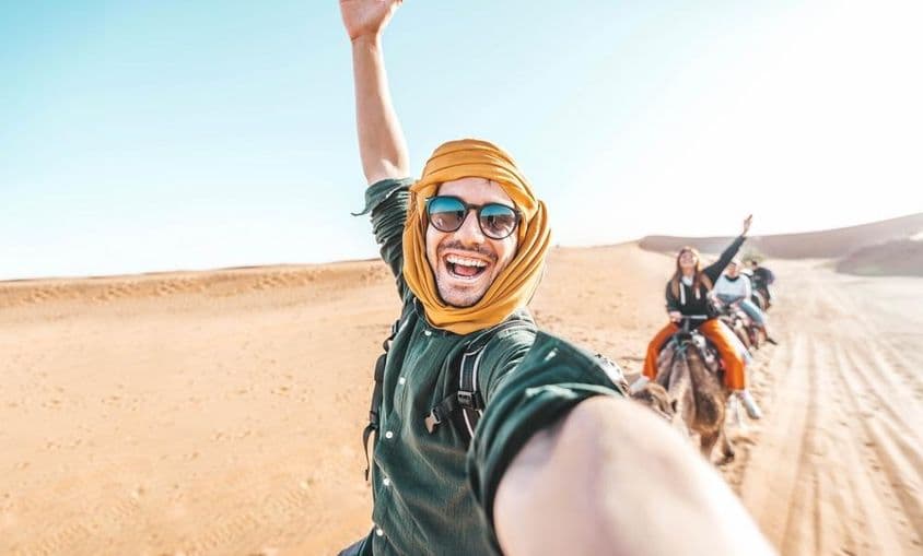 Turista feliz disfrutando paseo en camello por el desierto.