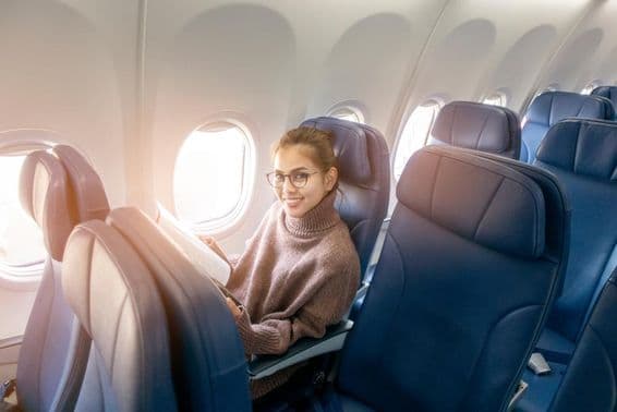 Mujer asiática leyendo una revista en un avión.