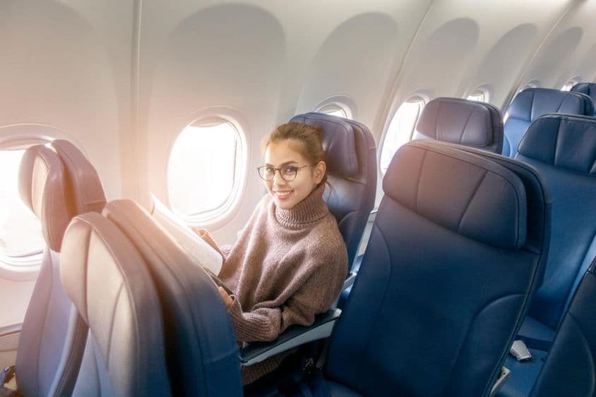 Mujer asiática leyendo una revista en un avión.