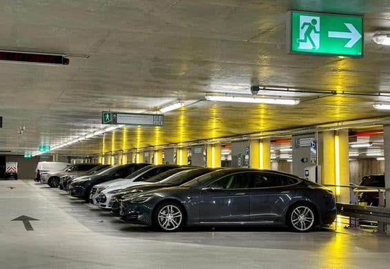 Luces de neón amarillas iluminan espacios reservados para vehículos eléctricos.