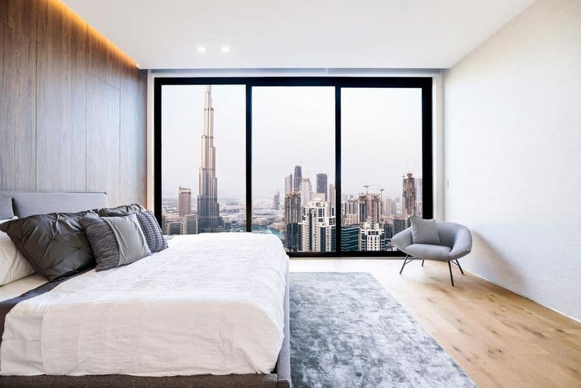 Dormitorio moderno con techo blanco y decoración de madera, vista de edificio alto y centro de Dubái.