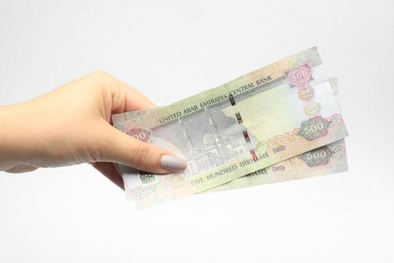 500 AED de moneda en la mano de una mujer.
