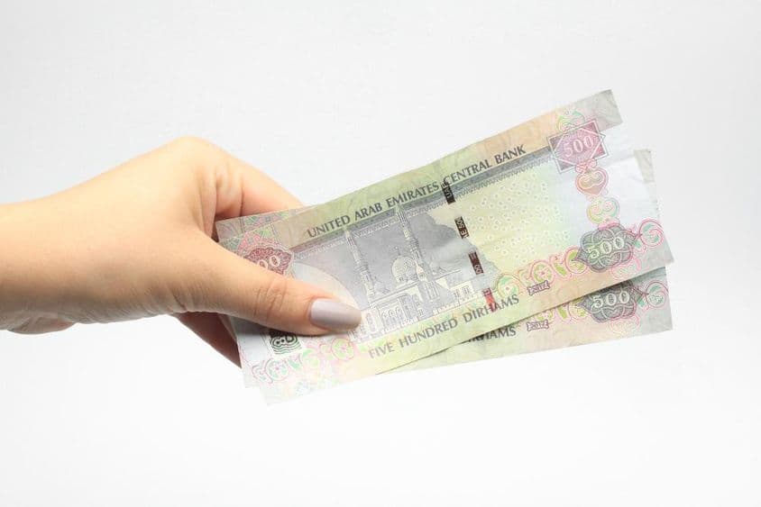 500 AED de moneda en la mano de una mujer.