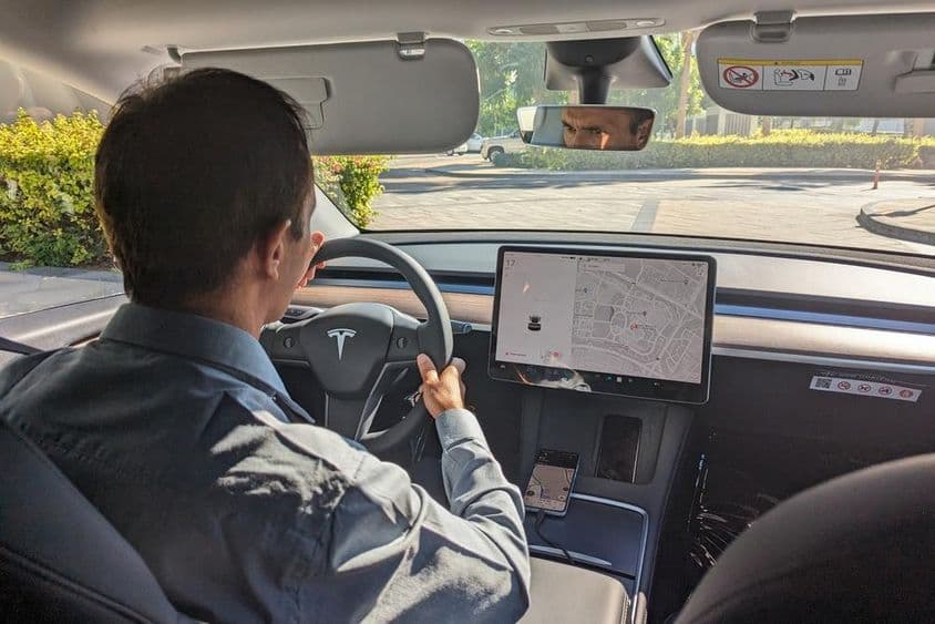 Conductor en Dubai manejando un coche Tesla por una carretera de la ciudad.