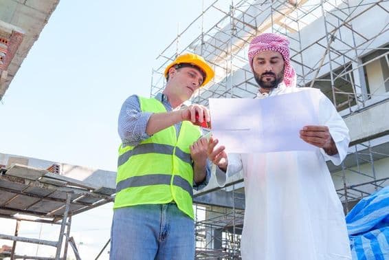Empresario árabe examinando un plano de ingeniería civil.